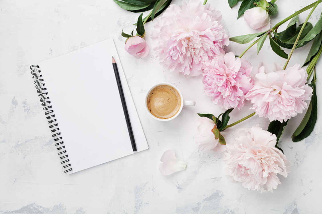 Morning coffee mug for breakfast, empty notebook, pencil and pink peony flowers. Flat lay. Woman working desk.